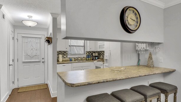 Une cuisine dotée d’un plan de travail en marbre, d’une horloge et d’un coin bar avec des tabourets.