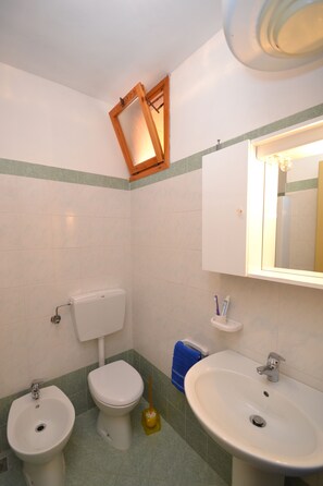 Ein Badezimmer mit Toilette, Bidet, Waschbecken und Spiegel.