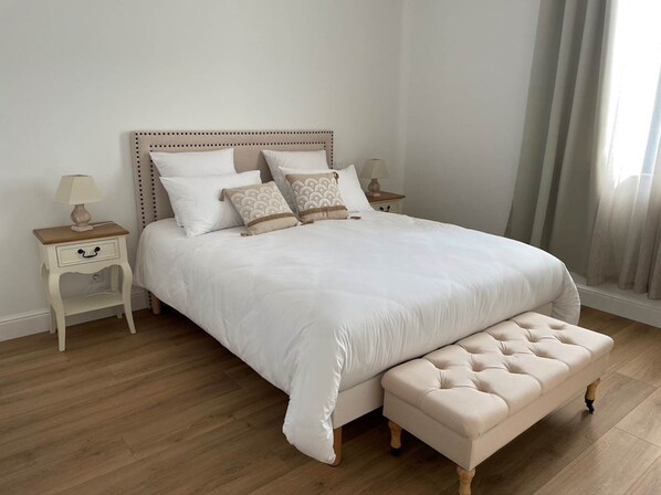 A neatly arranged bedroom with a large bed, two bedside tables, and a bench.