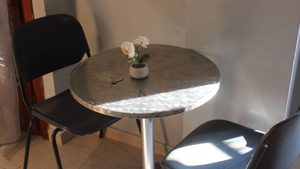 Une petite table ronde sur laquelle sont posés un pot d’orchidée et une clé, entourée de chaises noires.