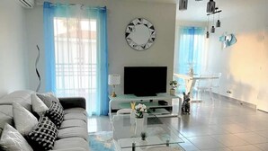 A modern living room with a sofa, TV, and glass coffee table.