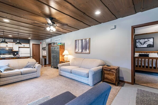 Ein gemütliches Wohnzimmer mit Holzboden, zwei Sofas, einem Couchtisch und einem Fernseher in einem Holzrahmen.