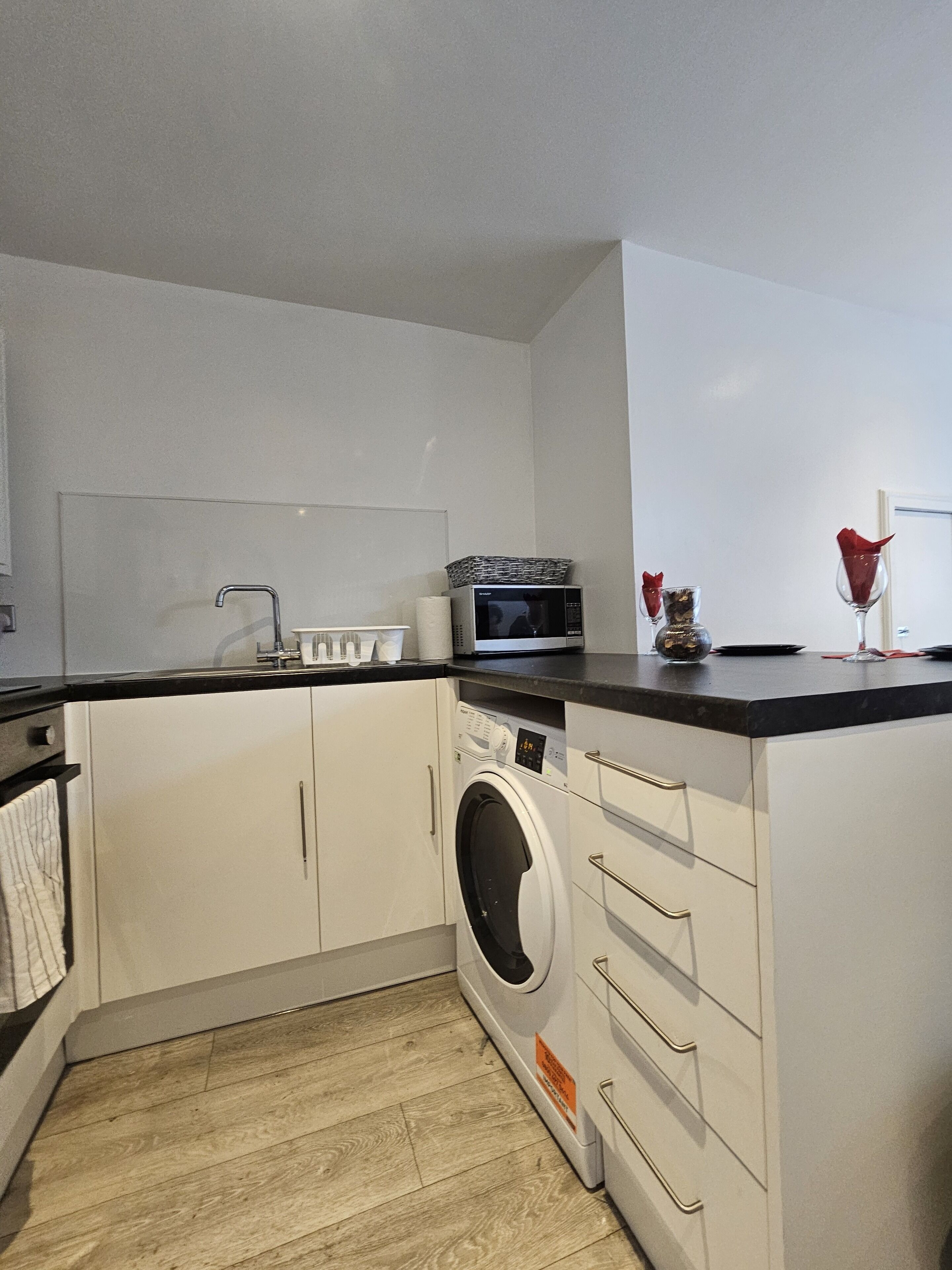 A compact kitchen with a washing machine, microwave, and a sink.