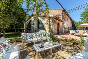 Eine Außenpatio mit einem Steingewölbe, weißen Möbeln und einer Pergola.