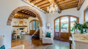 A spacious living area with wooden flooring, a chandelier, and arched brick walls. - Fonte Di Pierdo - Eleven Bedroom Villa, Sleeps 22 (Castelfranco di sotto)