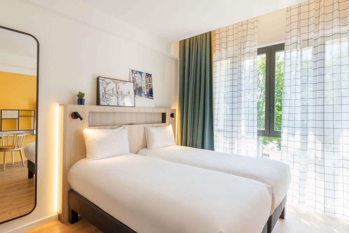 A hotel room with a bed, a desk, and a chair.