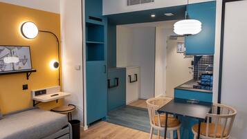 Un espacio habitable compacto con kitchenette, comedor y sofá.