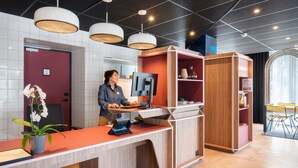 A modern reception desk with a computer, a potted orchid, and a wooden cabinet. - Aparthotel Adagio Access Rouen Centre Cathédrale (Rouen)