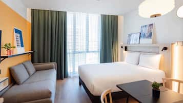 Una habitación de hotel con cama, sofá, mesa de comedor y una silla.