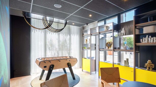 A modern room with a foosball table, a bookshelf, and a view of the street. - Aparthotel Adagio Access Rouen Centre Cathédrale (Rouen)
