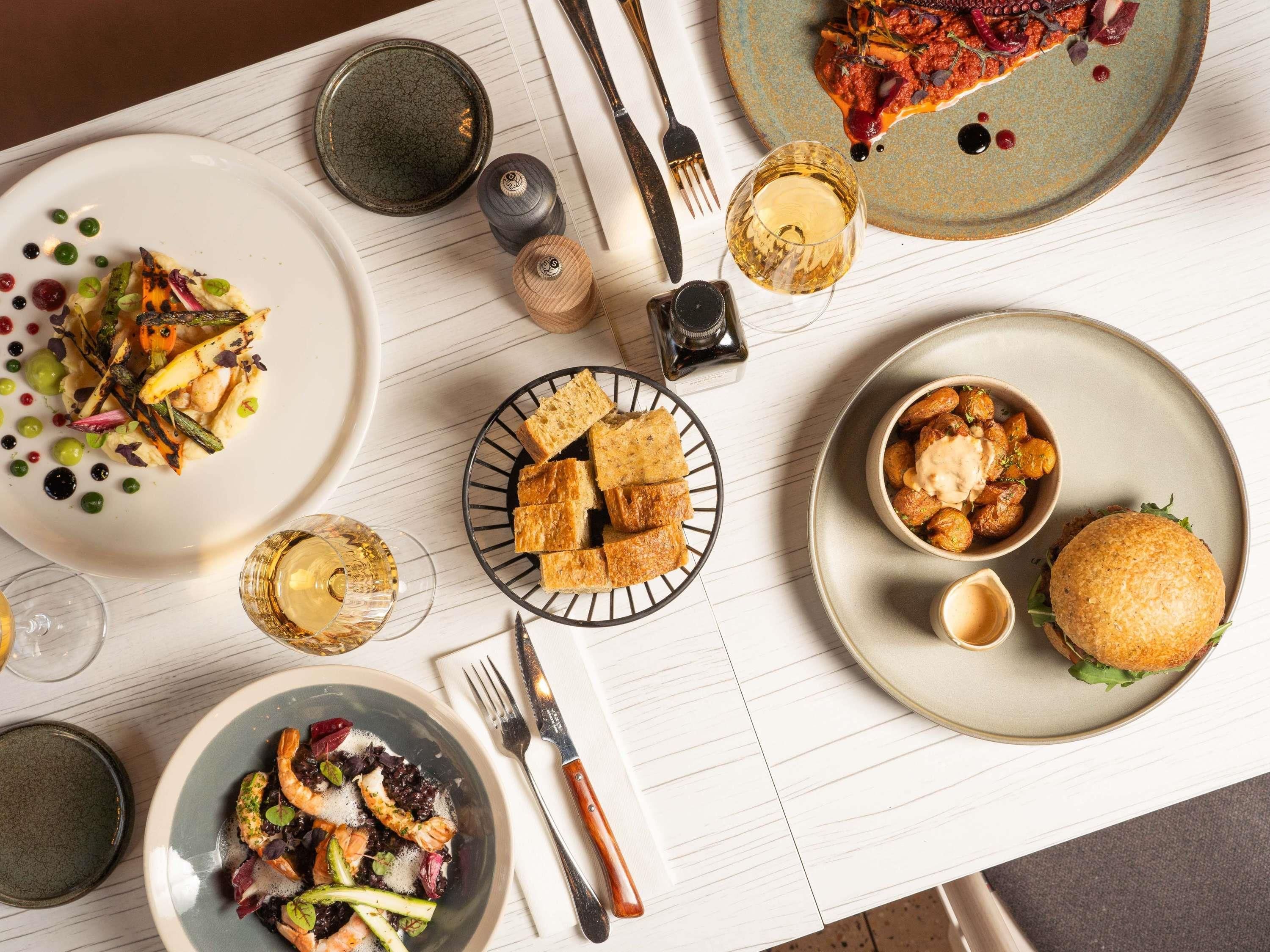 A dining table with various dishes, cutlery, and glasses.
