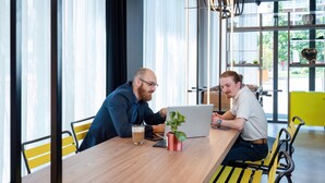 Two people at a wooden table with a laptop, a glass of beer, and a potted plant. - Aparthotel Adagio Access Rouen Centre Cathédrale (Rouen)