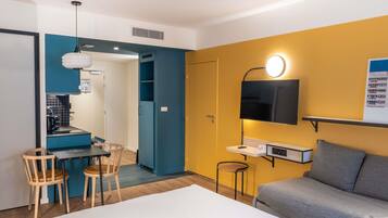 Une chambre d’hôtel moderne dotée d’un coin repas, d’un canapé et d’un téléviseur fixé au mur.