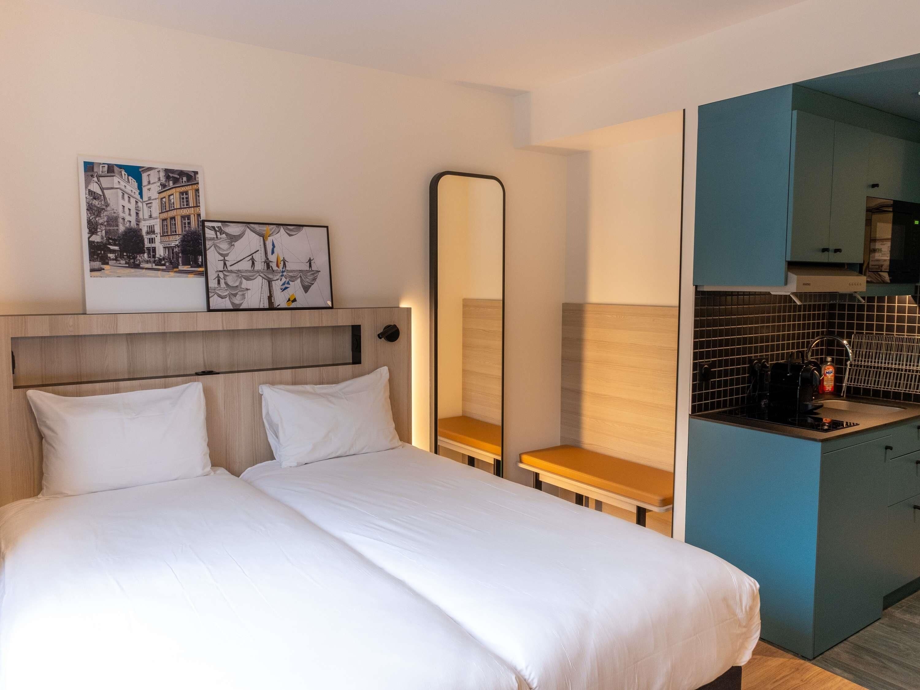 Habitación de hotel con cama, un escritorio pequeño, un espejo y kitchenette.