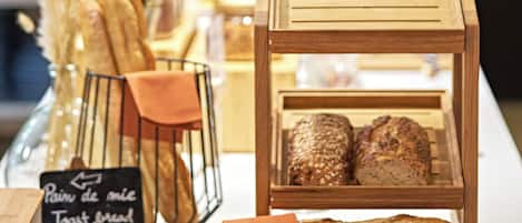 A bakery display with various breads and pastries, a sign indicating 'Pain de mie Toast bread', and a decorative arrangement of dried plants.
