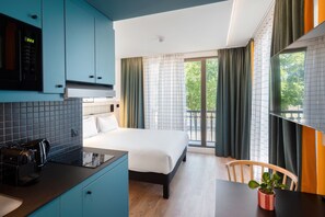 A modern hotel room with a bed, a small kitchenette, a dining area, and a balcony with curtains. - Aparthotel Adagio Access Rouen Centre Cathédrale (Rouen)