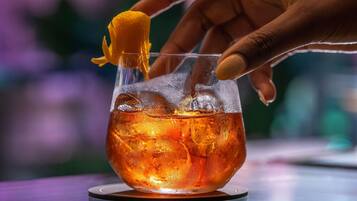 A hand holding a cocktail glass with ice cubes and a lemon garnish.