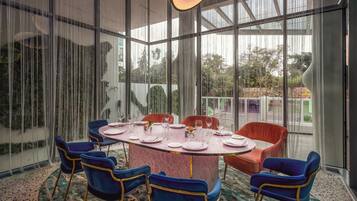 A modern dining area with a round table, blue chairs, and a patterned carpet.