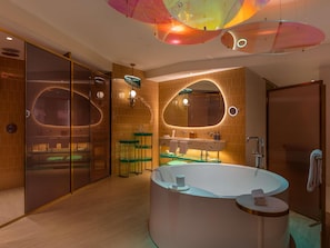 Une salle de bain moderne dotée d’une grande baignoire ovale, d’une cabine de douche en verre et d’un meuble-lavabo avec un miroir.