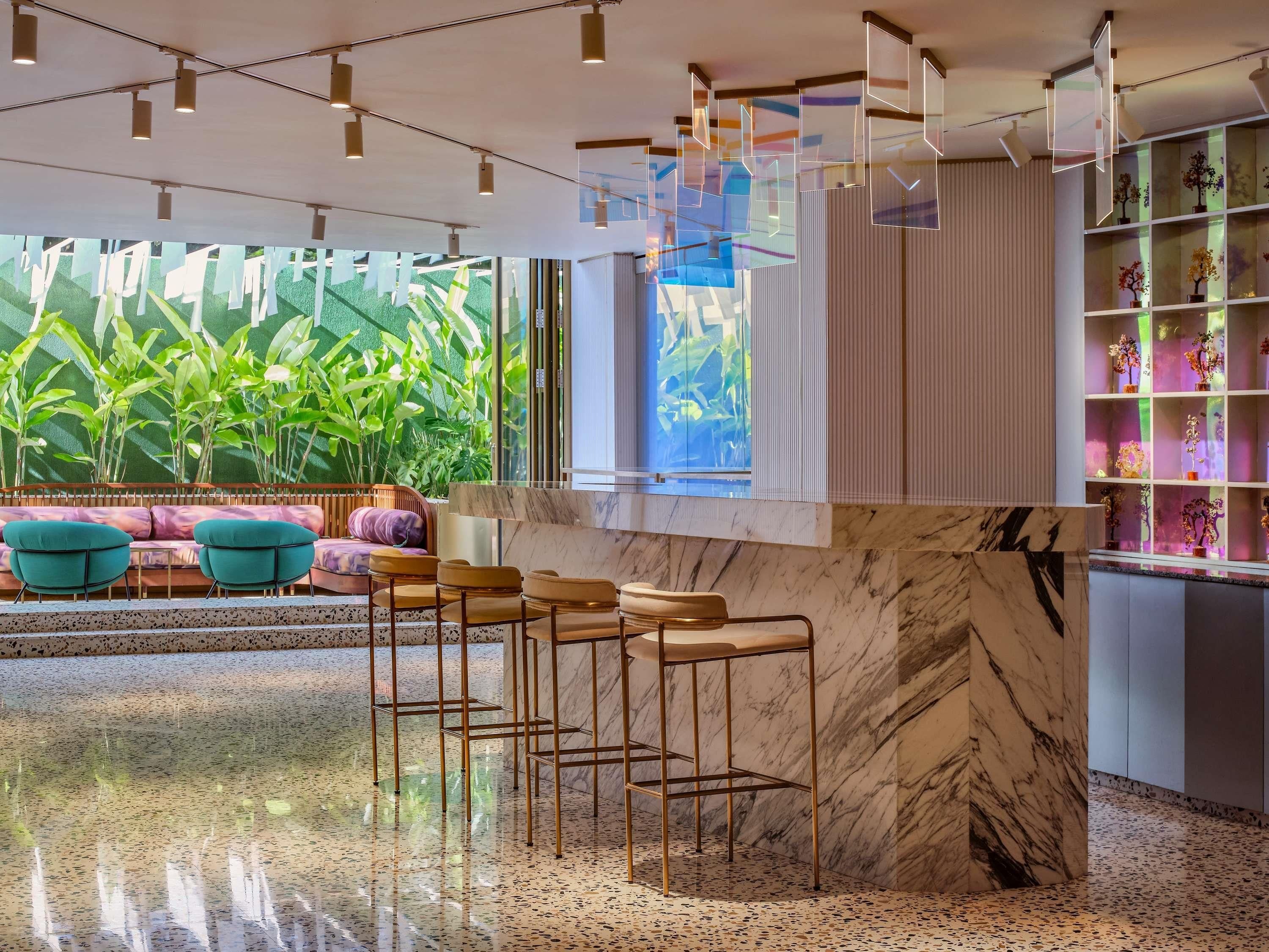 A modern interior with a bar area, seating, and a view of greenery.