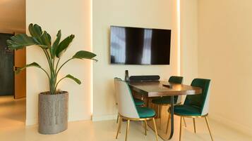 Un comedor con mesa, sillas, una planta en maceta y un televisor de pantalla plana montado en la pared.
