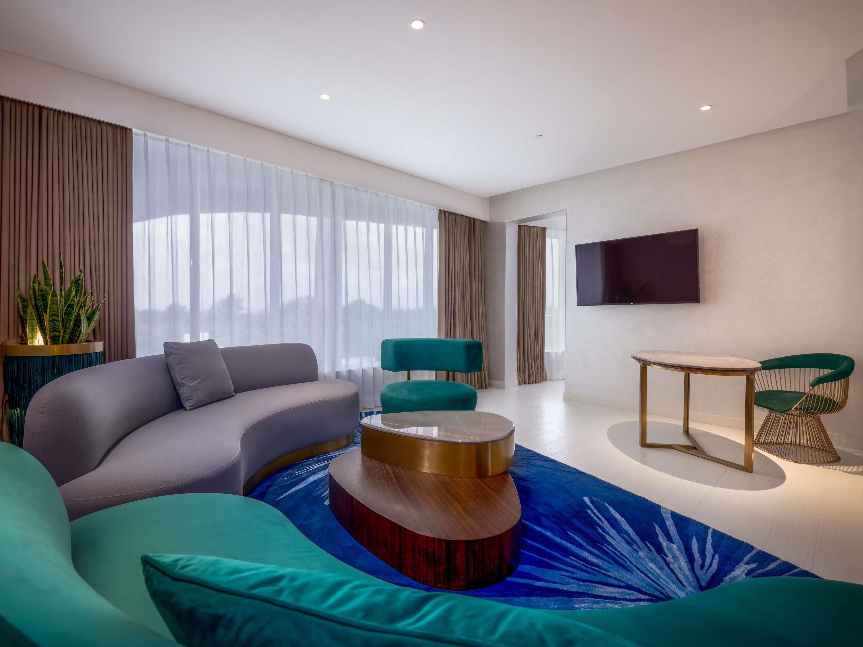 A modern living room with a sofa, a round coffee table, and a TV mounted on the wall.