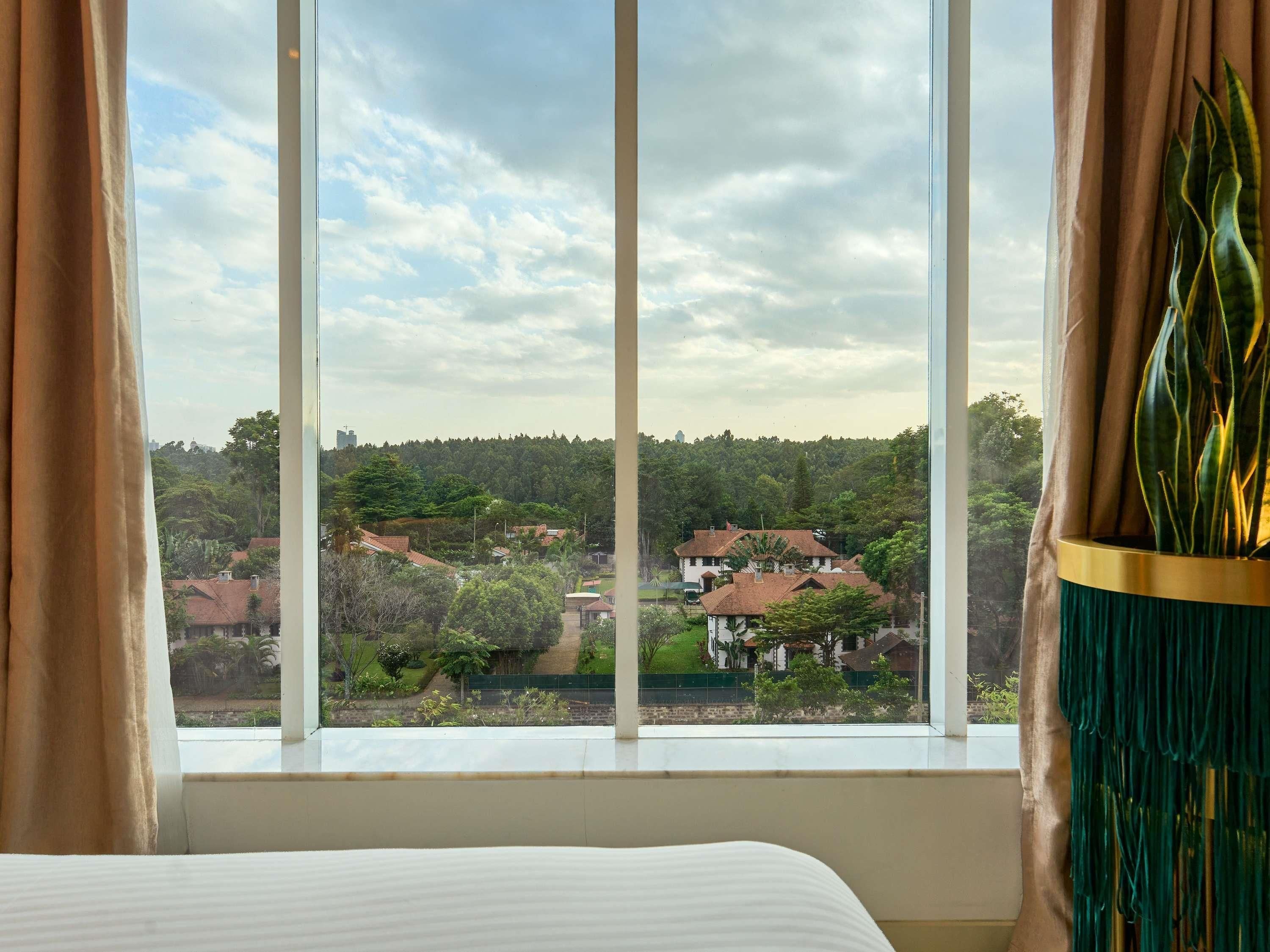 A room with a large window, curtains, and a plant on the windowsill.