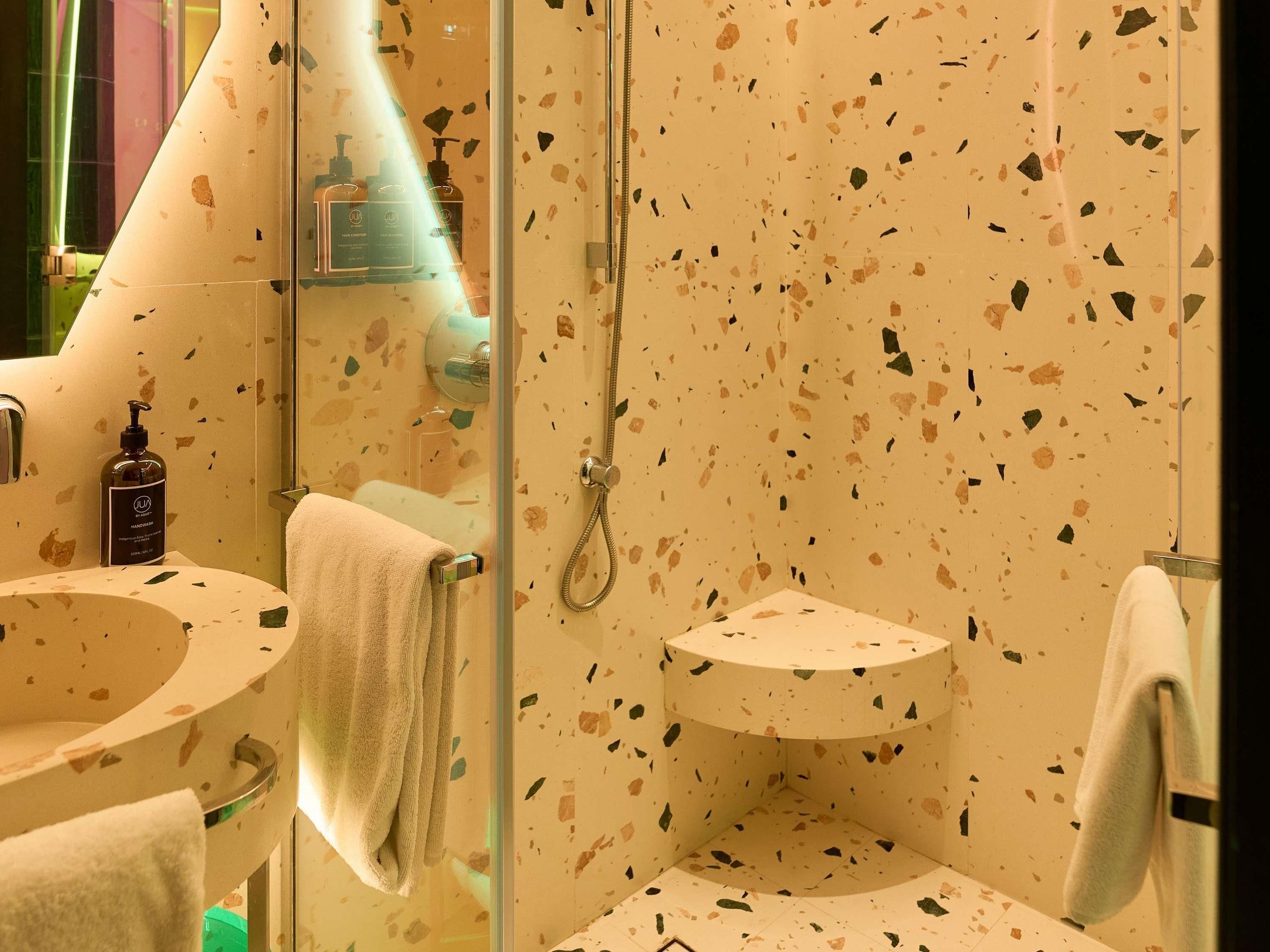 Un baño con cabina de ducha de vidrio, un lavamanos con espejo y un perchero para toallas.