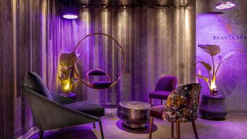 A modern lounge area with a circular hanging chair, a plush sofa, and a patterned armchair.