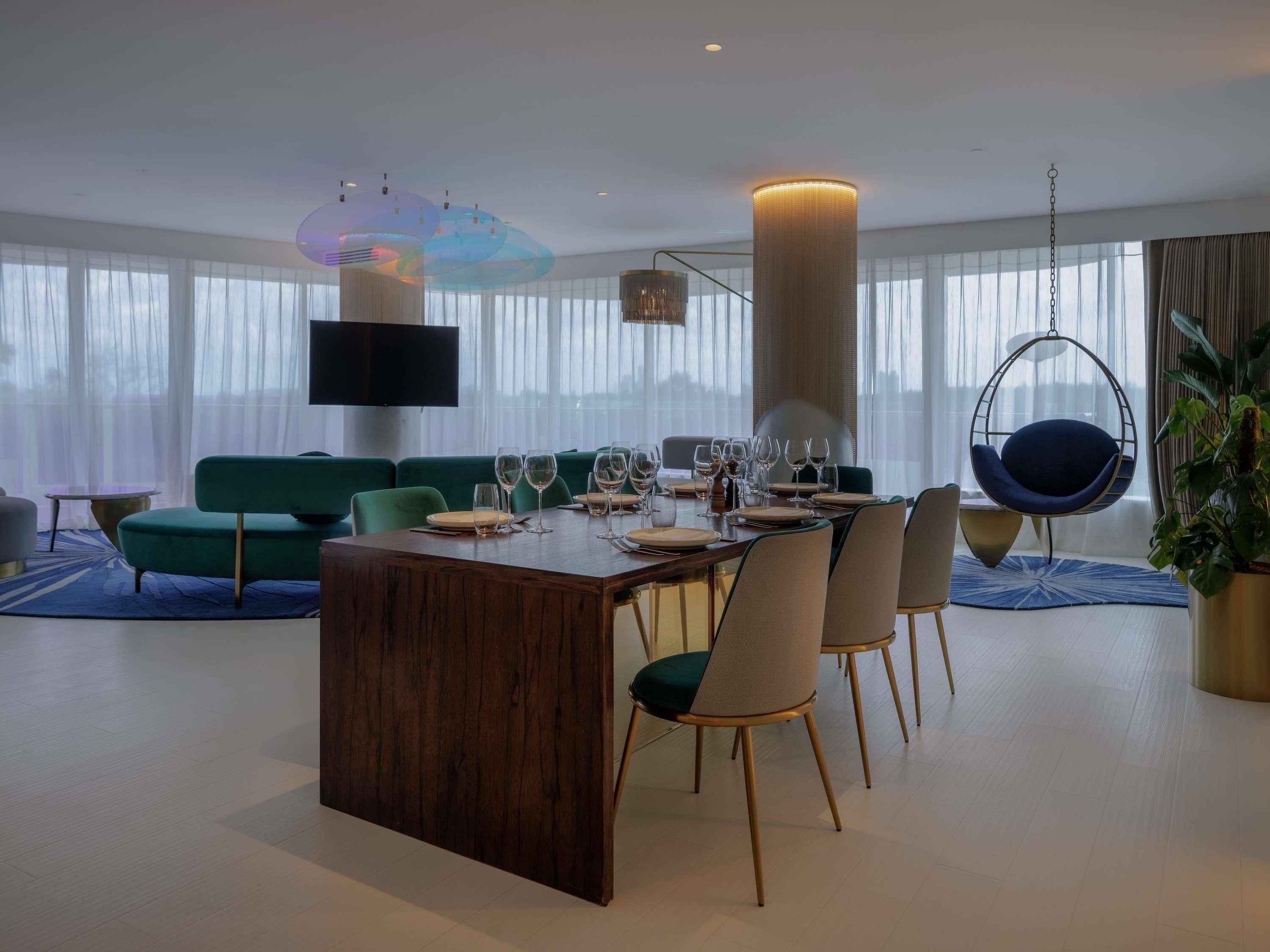 A modern dining area with a wooden table, chairs, and a hanging chair.