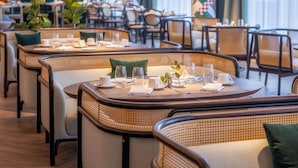 A restaurant with round tables, wicker chairs, and hanging pendant lights. - Gem Forest Hotel Nairobi - MGallery Collection (Nairobi)