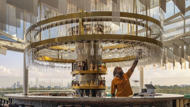 A bar area with a circular bar counter, multiple seating arrangements, and a city view. - Gem Forest Hotel Nairobi - MGallery Collection (Nairobi)