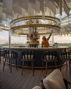 A bar area with a circular bar counter, multiple seating arrangements, and a city view. - Gem Forest Hotel Nairobi - MGallery Collection (Nairobi)