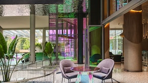 A modern interior with a glass table and two chairs, a staircase, and a view of greenery outside. - Gem Forest Hotel Nairobi - MGallery Collection (Nairobi)