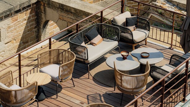 A terrace with wicker furniture, stone walls, and a view of a river and buildings. - Hotel Fort St Laurent Lyon - Handwritten Collection (Lyon)