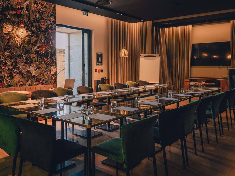 Un salón de conferencias con una larga mesa, sillas y una pantalla para proyector.