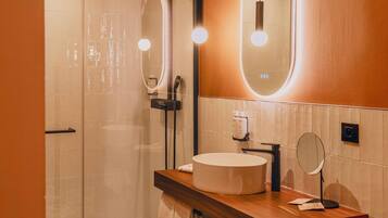 A modern bathroom with a glass-enclosed shower, a round mirror, and a wooden vanity with a sink.