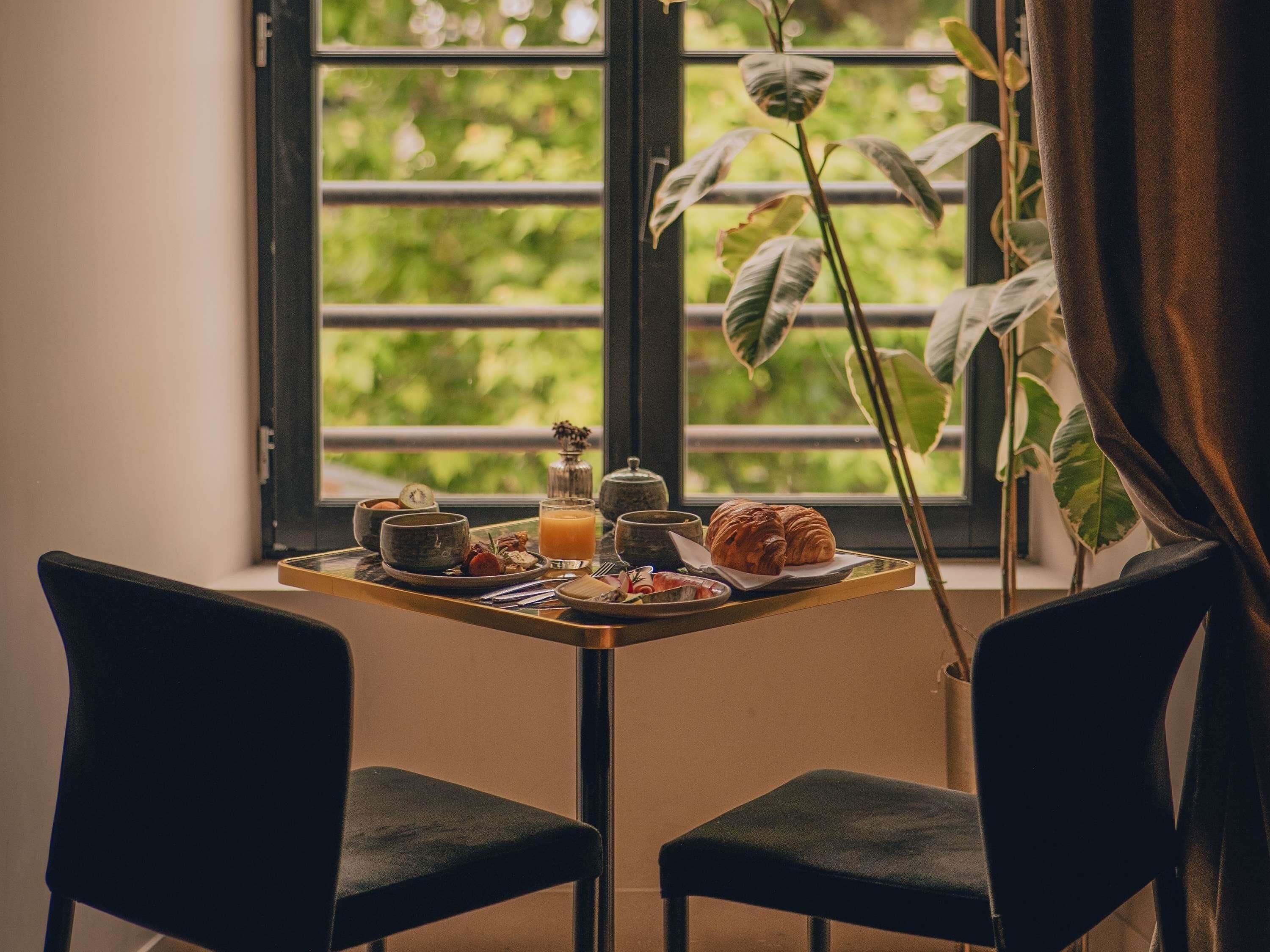 Una mesa de desayuno con un croissant, un vaso de jugo de naranja y una tetera.