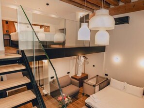 A modern hotel room with a glass staircase, a bed, a seating area, and pendant lighting. - Hotel Fort St Laurent Lyon - Handwritten Collection (Lyon)
