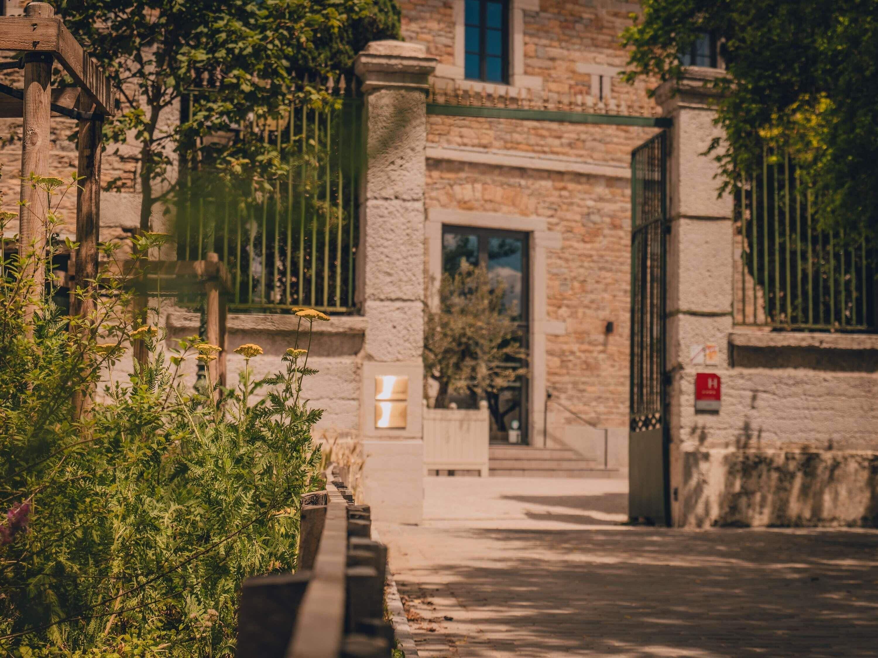 Un bâtiment en pierre doté d’une entrée fermée par un portail, d’une petite fenêtre et d’une porte.