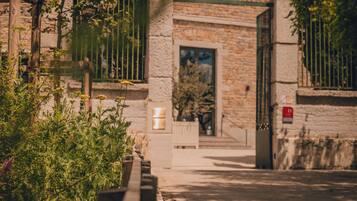 Un bâtiment en pierre doté d’une entrée fermée par un portail, d’une petite fenêtre et d’une porte.