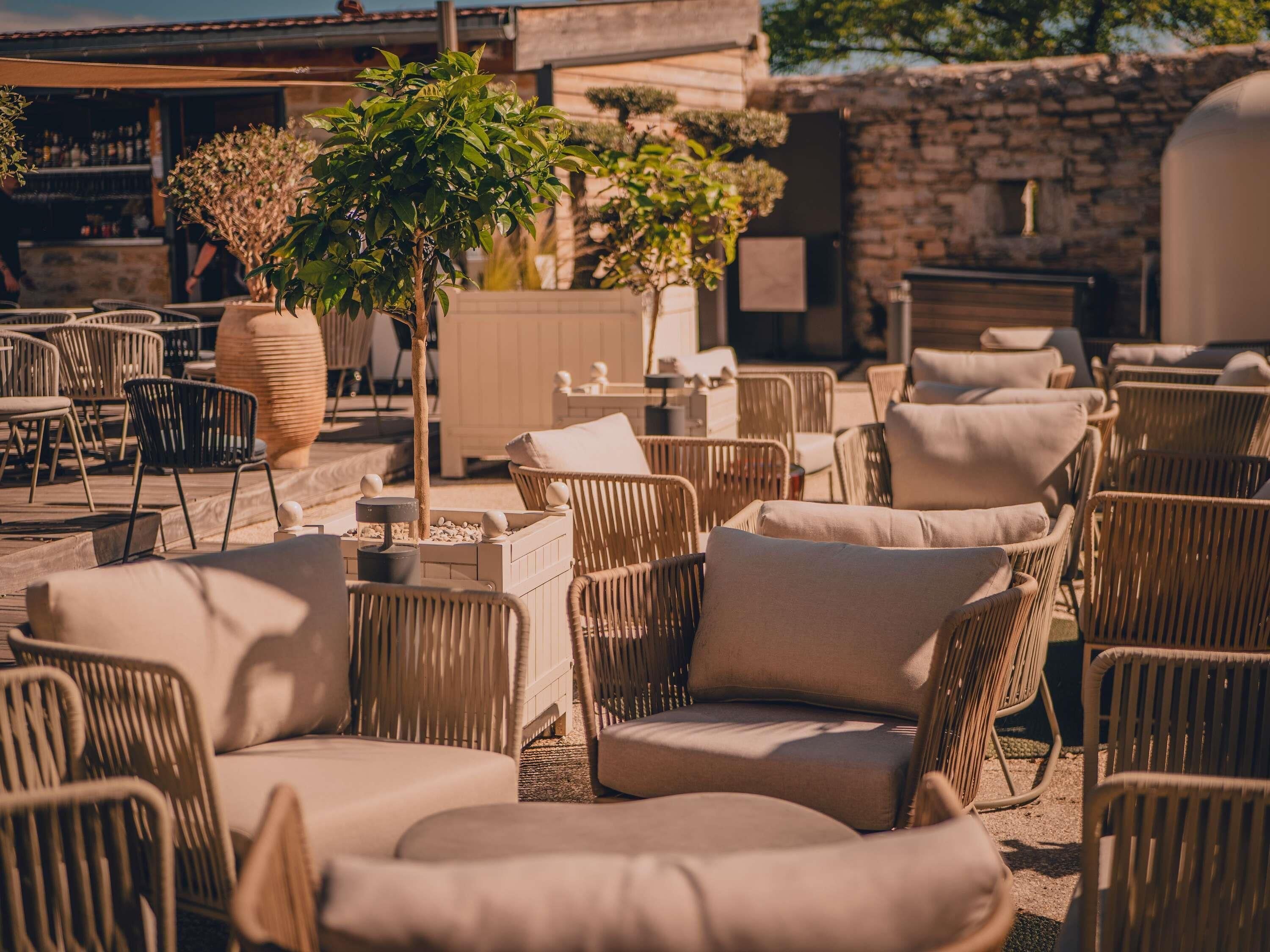 An outdoor seating area with wicker chairs and a large planter with a tree.