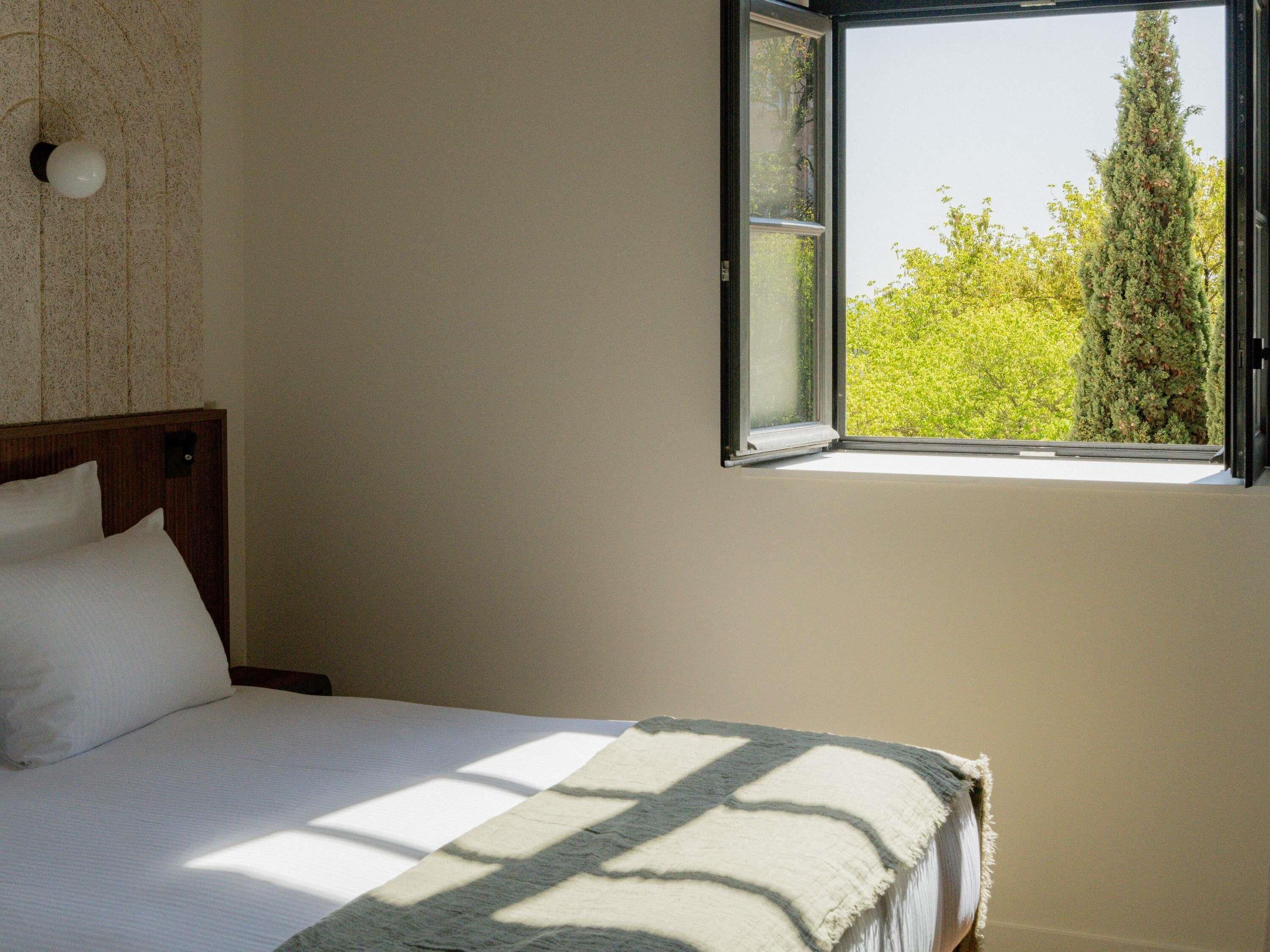 A bedroom with a bed, a window, and a wall with a textured pattern.