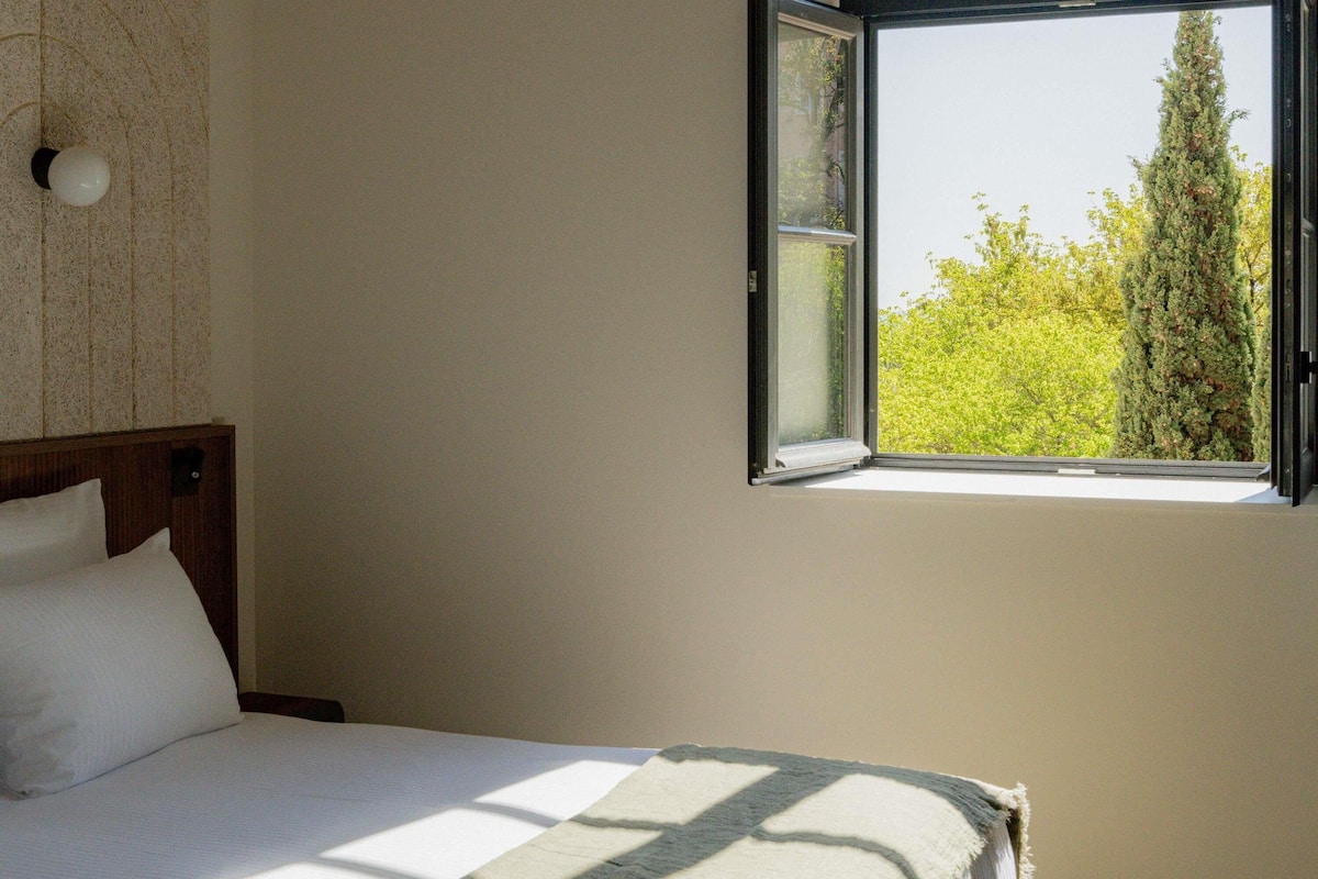 A bedroom with a bed, a window, and a wall with a textured pattern.