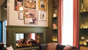Ein gemütlicher Loungebereich mit Kamin, Sitzgelegenheiten und einer Bücherwand voller Bücher und Dekoration.