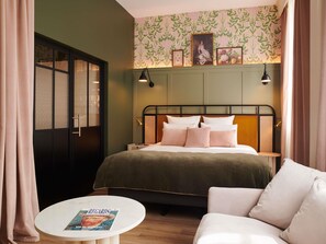 A hotel room with a bed, bedside tables, a round table with a magazine, a sofa, and a wardrobe. - Square Lodge Hotel La Roche Sur Yon - Handwritten Collection (La Roche-sur-Yon)