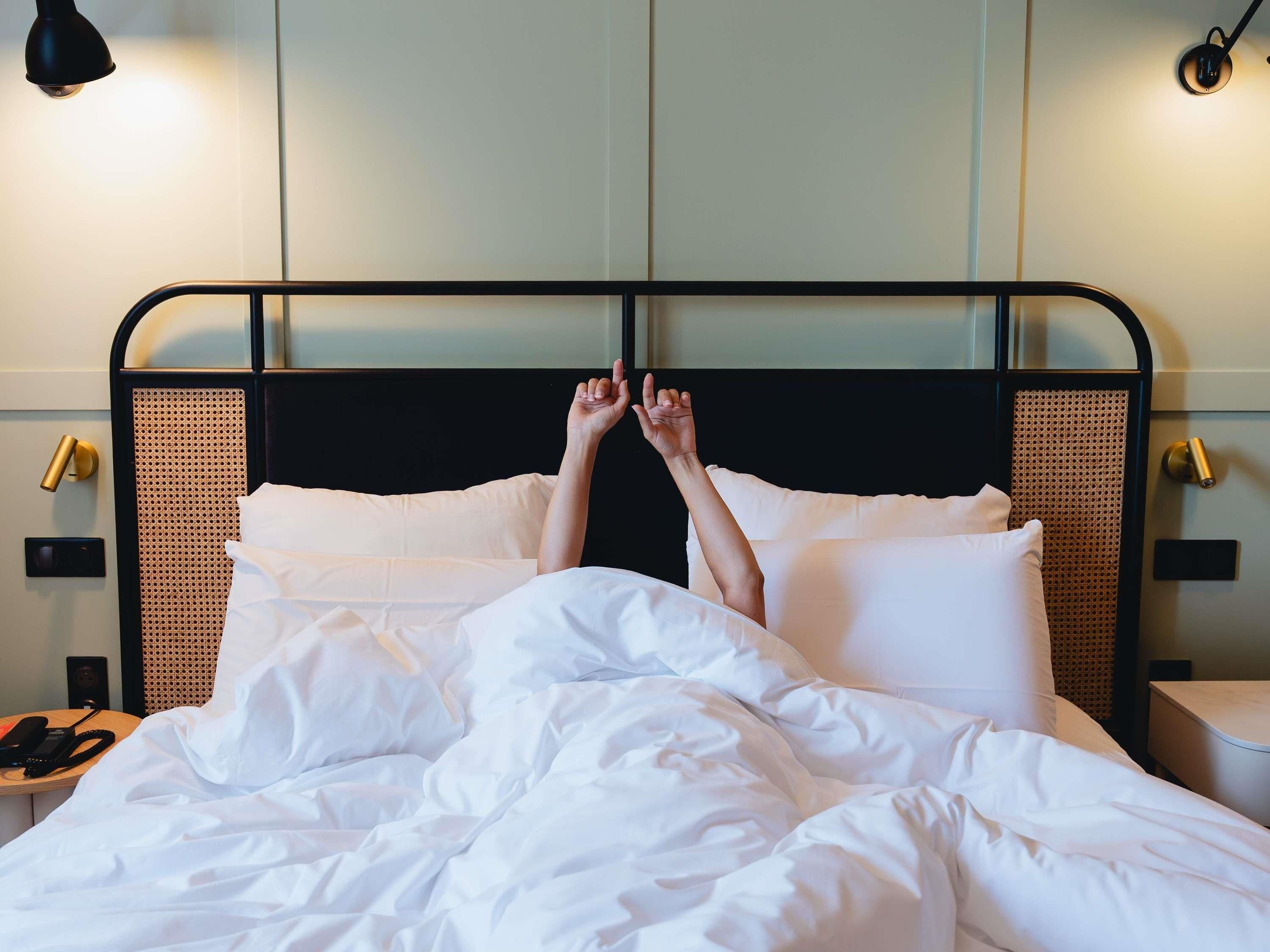 A hotel room with a bed, white bedding, a black metal headboard, and two bedside lamps.