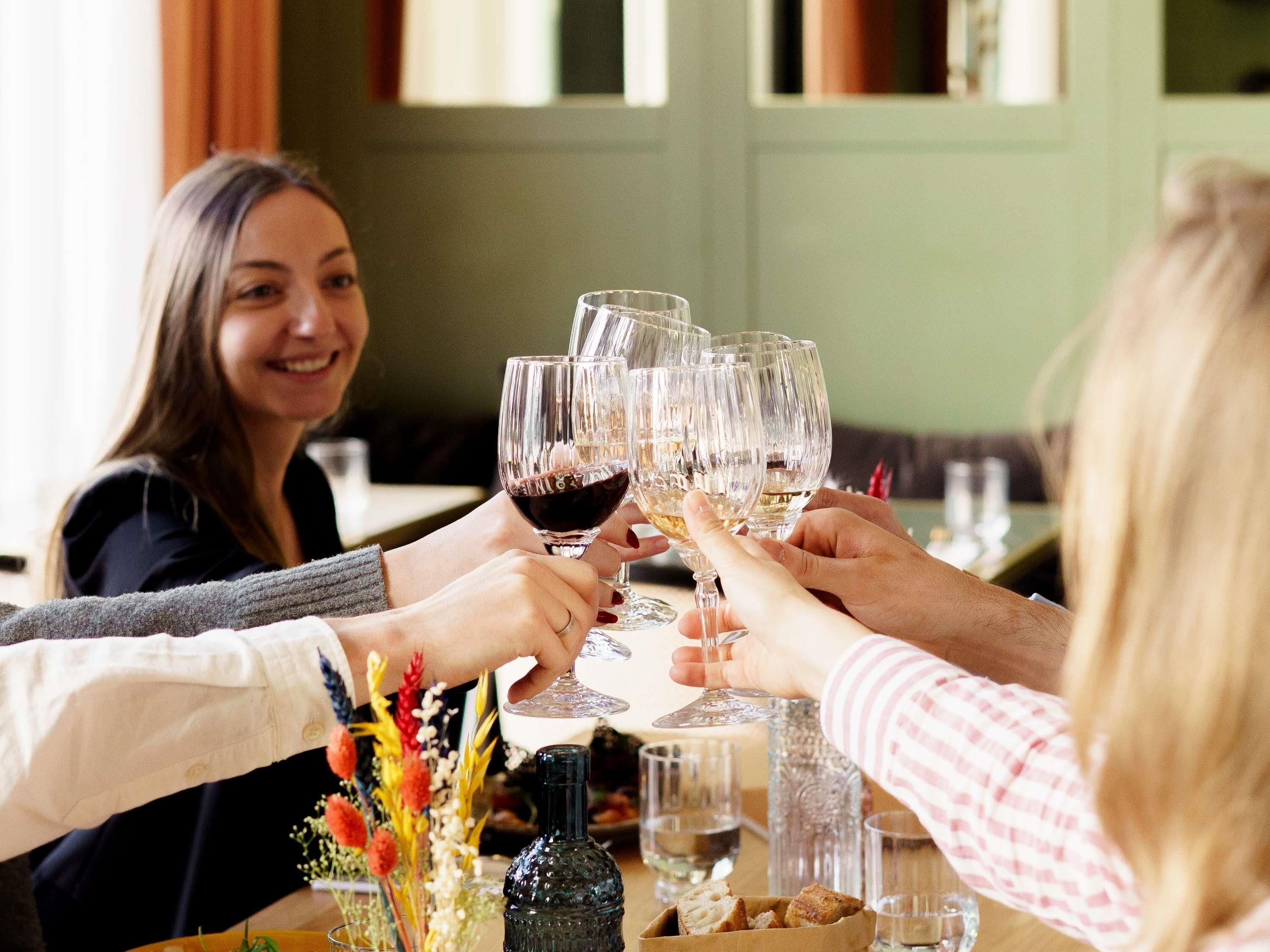 Un grupo de personas brindando con copas de vino en una mesa con una botella y vasos de agua.