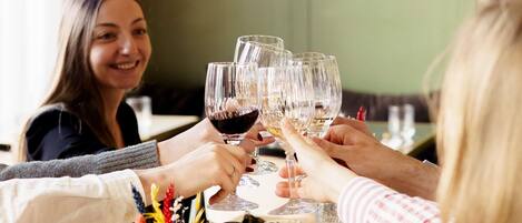 Un grupo de personas brindando con copas de vino en una mesa con una botella y vasos de agua.