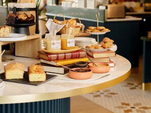A buffet with various baked goods, books, and jars of preserves.